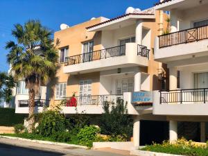 un grande edificio con balconi e una palma di Lighthouse Beach apartment a Paphos