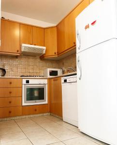 una cucina con frigorifero bianco e armadietti in legno di Lighthouse Beach apartment a Paphos