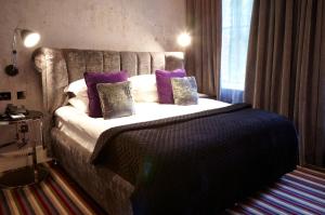 a bedroom with a large bed with purple pillows at Malmaison London in London