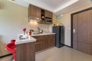een keuken met houten kasten en een zwarte koelkast bij Квартира вид на бассейн NBC S402 by IBG Property in Nai Harn Beach
