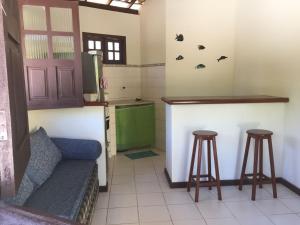 a kitchen with a counter and two stools in a room at Chalés Rio Bonito in Imbassai
