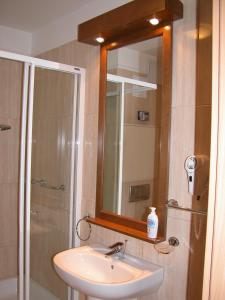 a bathroom with a sink and a shower and a mirror at Apartman Golf Lux in Bük