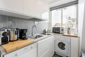 une cuisine avec un évier et une machine à laver dans l'établissement Appart Terrasse Vue Tour Eiffel, à Paris 5 autres photos