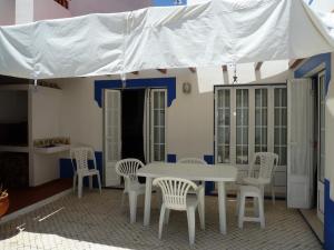 a white table and chairs under a white umbrella at CASA DA BARRA AZUL by Stay in Alentejo in Vila Nova de Milfontes