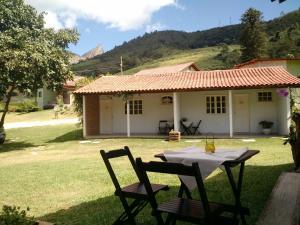 uma mesa e cadeiras em frente a uma casa em Passarinhada Hospedagem em Domingos Martins