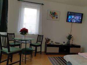 ein Wohnzimmer mit einem Tisch, Stühlen und einem Fenster in der Unterkunft Relax Apartman Veresegyház in Veresegyház