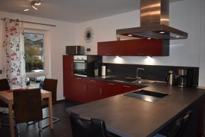 eine Küche mit roten Schränken und einer schwarzen Arbeitsplatte in der Unterkunft FEWO Excellence in Traben-Trarbach