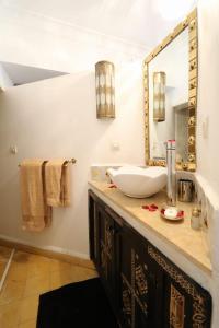 ein Bad mit einem Waschbecken und einem Spiegel in der Unterkunft La Voûte Étoilée in Marrakesch