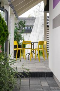 a patio with yellow chairs and a table at Apartamenty Lawendowo Mi Raz Dwa Trzy in Kopalino