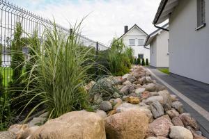 a garden of rocks and plants next to a house at Apartamenty Lawendowo Mi Raz Dwa Trzy in Kopalino