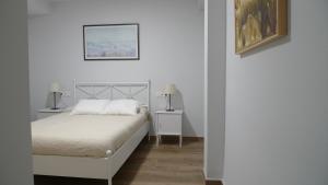 a white bedroom with a white bed and two lamps at Living Triana House in Seville