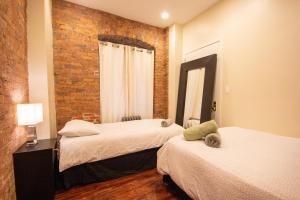 a bedroom with two beds and a brick wall at STUDIO PLUS - 2 Bedroom Apartment in Midtown in New York