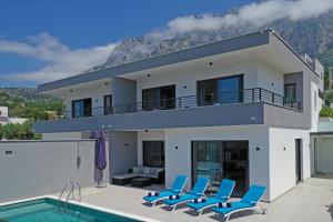 馬卡爾斯卡的住宿－Villa Alexandra - Makarska，一座带游泳池和蓝色椅子的房子
