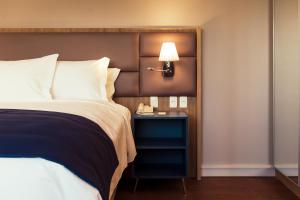 a bedroom with a bed and a nightstand with a lamp at Quality Porto Alegre in Porto Alegre