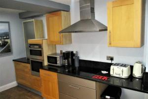 una cucina con piano di lavoro nero e armadietti in legno di COOKS CABIN a Plymouth