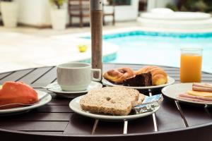 a table with plates of food and a cup of orange juice at Pousada Blue Marlin in Búzios