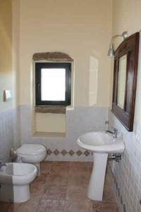 a bathroom with a toilet and a sink and a window at La Casedda in Luogosanto