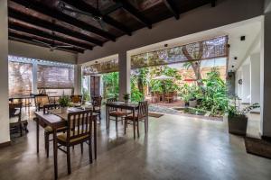 uma sala de jantar com mesas e cadeiras e janelas grandes em Sayura House em Colombo