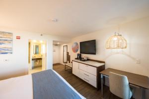 a bedroom with a bed and a desk with a television at SeaCrest Oceanfront Hotel in Pismo Beach