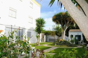 ein Garten mit Palmen und einem weißen Gebäude in der Unterkunft Arabias Loft Caños de Meca in Los Caños de Meca