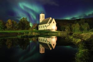 ein Bild einer Kirche mit einer Reflexion im Wasser in der Unterkunft Melbu Hotell in Melbu