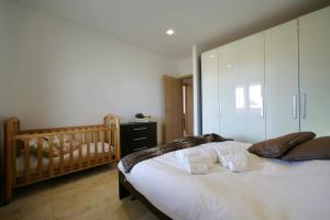 a bedroom with a crib and a large bed at VILLA DELFINI 2-12 Pax in San Vito lo Capo