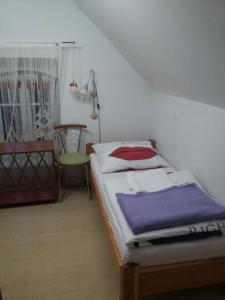 a small bed in a room with a chair at Biały na poddaszu in Polanica-Zdrój