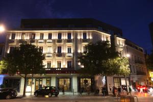 a large white building with cars parked in front of it at Hotel De France in Valence