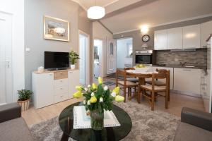 eine Küche und ein Wohnzimmer mit einem Tisch und einer Vase aus Blumen in der Unterkunft Apartman Slavica in Rijeka