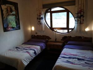 two beds in a room with a window at Casa Rural Ruralba in Alba de los Cardaños