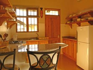 cocina con nevera blanca y armarios de madera en Milimani Cottages, en Usa River