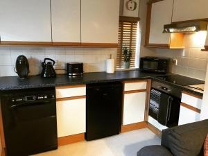 a kitchen with black appliances and a black dishwasher at Clarabel's Guest House- The Nook in Wombourn