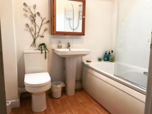 a bathroom with a toilet and a sink and a bath tub at Clarabel's Guest House- The Nook in Wombourn