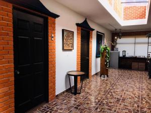 a hallway with a black door and a brick wall at Hotel Bugambilias Rooms in Tequisquiapan
