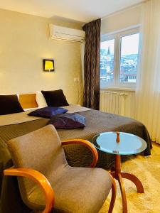 a hotel room with two beds and a chair and a table at Halvat Guesthouse in Sarajevo