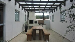 a patio with a wooden table in a building at Loft no Residencial Marbella à 300 metros da praia in Bombinhas