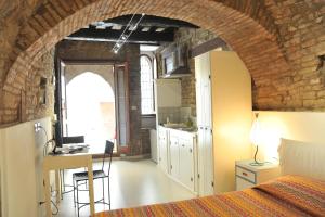 a bedroom with a brick wall and a bed and a kitchen at Vico Del Poeta in Assisi