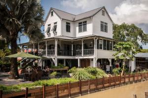 ein weißes Haus am Fluss mit Tischen und Stühlen in der Unterkunft Boutique Hotel Peperpot in Meerzorg