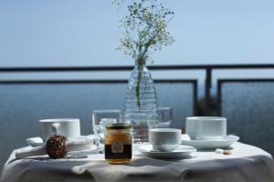 una mesa con un paño de mesa blanco con tazas y un bastidor en B&B Hotei, en Catania