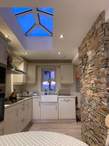 a kitchen with white cabinets and a stone wall at Fairview House in Portstewart
