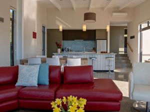 a living room with a red couch and a kitchen at Kotare Point Paradise - Akaroa Holiday Home in Akaroa