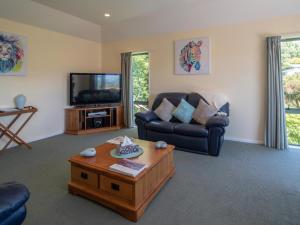 a living room with a couch and a tv at Rue Noyer Lookout - Akaroa Holiday Home in Akaroa