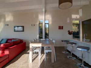 アカロアにあるKotare Point Paradise - Akaroa Holiday Homeのリビングルーム(赤いソファ、テーブル付)