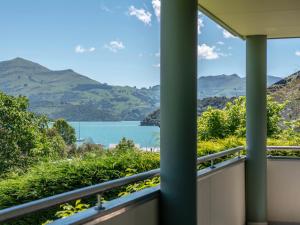 a balcony with a view of a lake and mountains at Rue Noyer Lookout - Akaroa Holiday Home in Akaroa