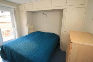 ein kleines Schlafzimmer mit einem blauen Bett und einem Schreibtisch in der Unterkunft Appartement Sincfala in Knokke-Heist