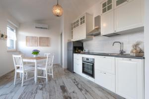 a kitchen with white cabinets and a table and chairs at Il bianconido in Castel Gandolfo