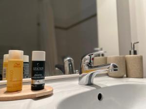 - un lavabo dans la salle de bains avec une bouteille de bouche et un miroir dans l'établissement La réserve 1 et 2,Maisons de vacances en Baie de Somme, à Saint-Valery-sur-Somme