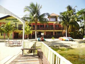 a building on the beach with palm trees in front of it at Alan's Paradise Hotel in Placencia Village