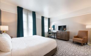 a hotel room with a bed and a chair and a television at Magnolia Hotel Omaha in Omaha