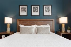 a bedroom with a white bed with three pictures on the wall at Magnolia Hotel Omaha in Omaha